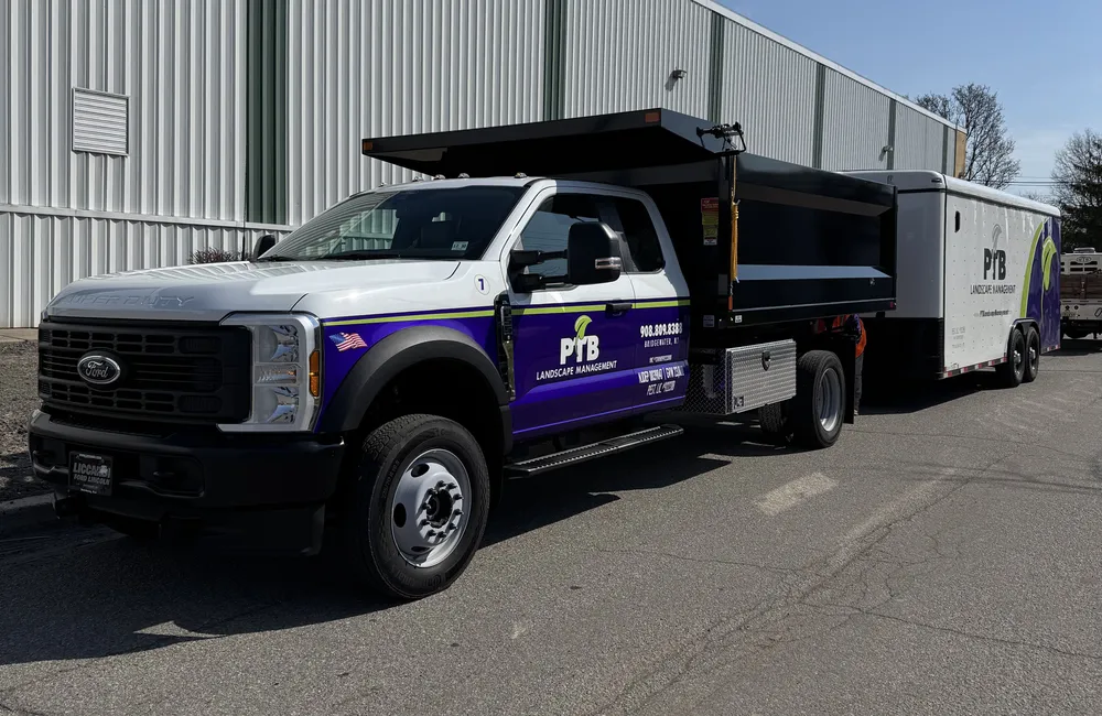 PTB Landscape Management branded truck and enclosed trailer parked at a commercial property in New Jersey